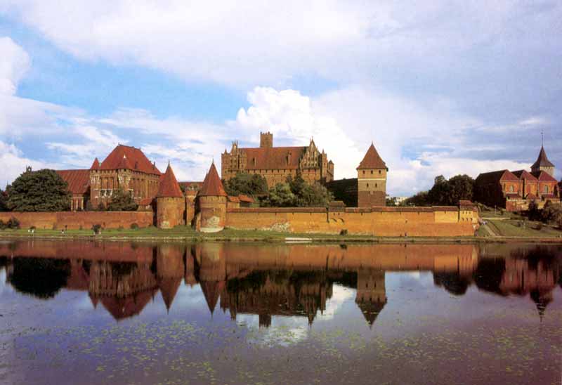 La
                Commanderie de Malbork en soirée se reflétant dans les
                eaux calmes de la Nogat