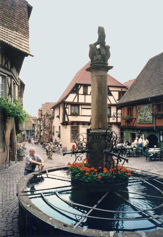 Riquewihr : Jean-Paul devant la fontaine du
                  Dolder en haut de la Grande Rue
