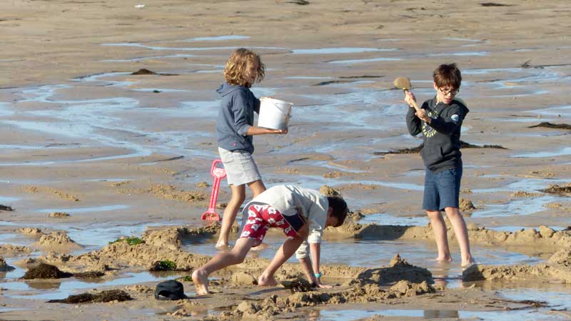 Plage de Luc-sur-Mer à marée basse : Quentin,
                  Maël et Gabriel pataugent dans l'eau et le sable