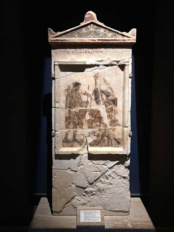 Vergina Stele funeraire en marbre deux hommes -
                  un père, assis, et son fils, debout - près d'une
                  femme (probablement l'épouse du fils) et d'un petit
                  garçon avec inscription des noms des défunts
                  (330-320 B.C.)